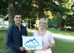 Gemeindepräsidentin der Gemeinde Flühli-Sörenberg, Sabine Wermelinger nimmt das Label von Moreno Donato, Vorsitzender SAB-Jugendforum entgegen.